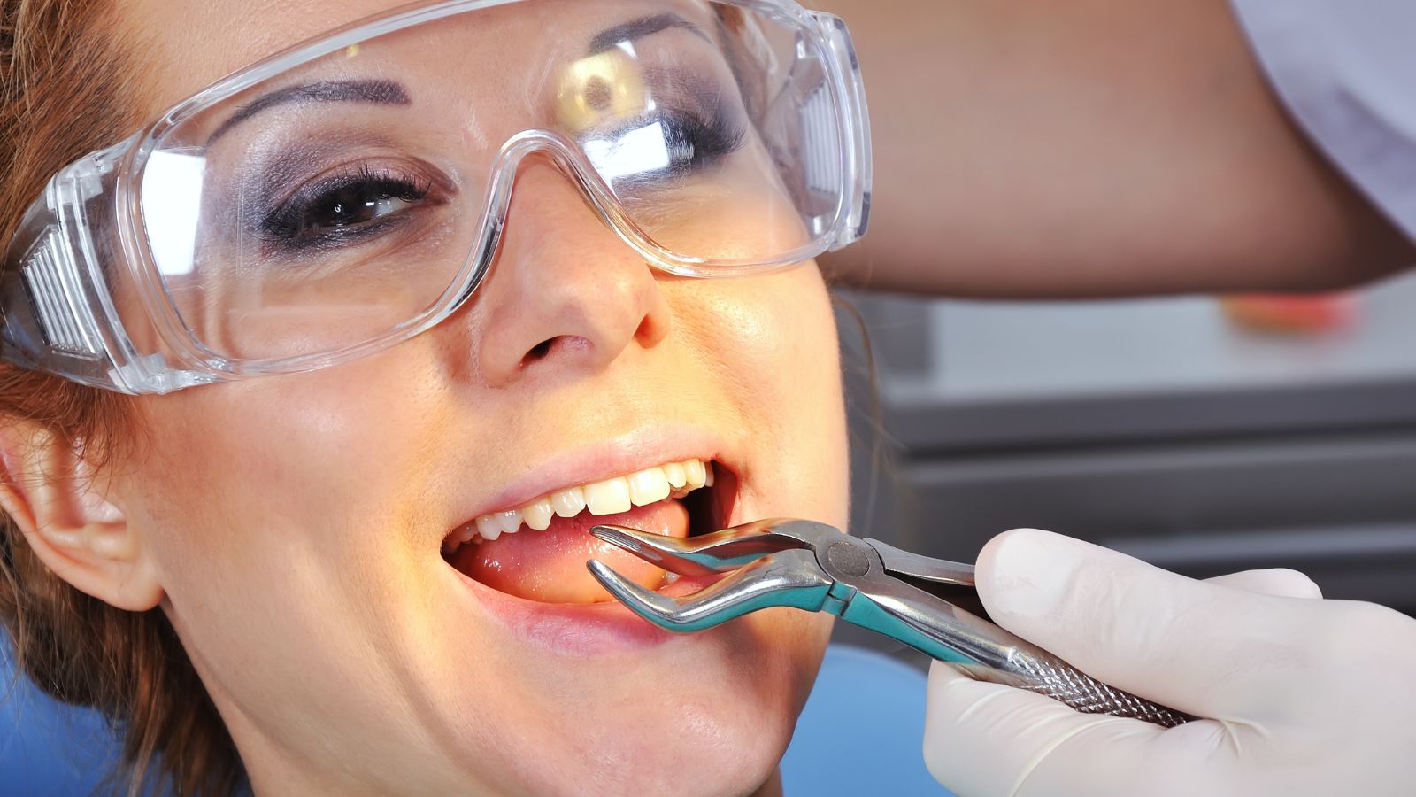 Doktor, diş çekimi için ağız açık şekilde oturan hastayı dental ekipmanla muayene ediyor